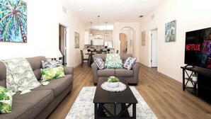 A modern living room with two sofas, a coffee table, and a TV on a stand. - Family Ties at Bahama Bay - Luxe 3BR Townhouse (Davenport)