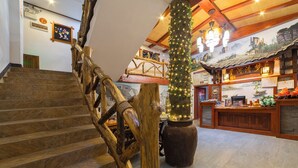 A staircase with a wooden handrail leading to a reception area with a traditional design, including a wooden counter and a mural on the wall. - Zhangjiajie Xinghe Qingmeng Folk-style Inn (Zhangjiajie)