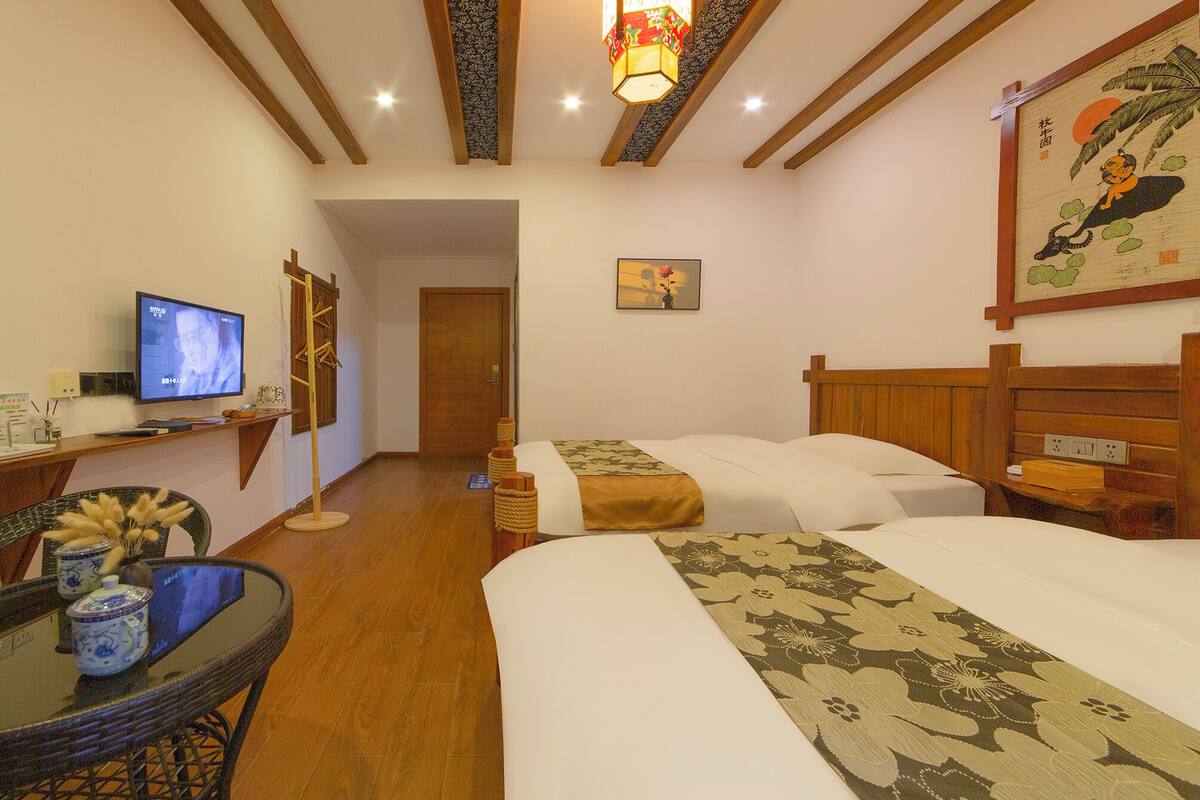 Une chambre d’hôtel avec deux lits, une télévision, un bureau avec un ordinateur et un tableau décoratif.