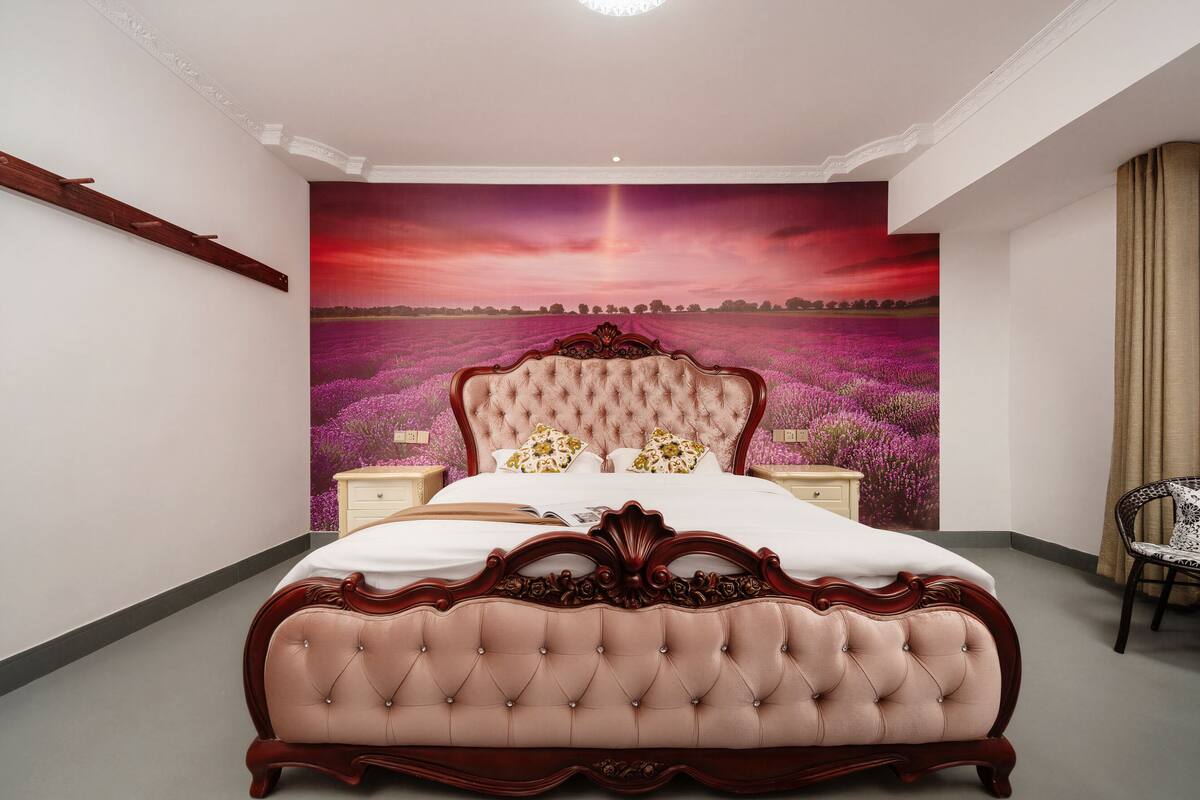 Une chambre à coucher avec un grand lit, une table de chevet, une chaise et une fresque murale.
