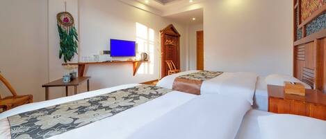 A hotel room with two beds, a television, a desk with a computer, and a decorative wall hanging.