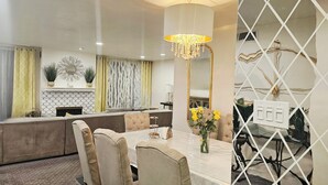 A modern dining area with a chandelier, a dining table with chairs, a sofa, and a decorative mirror. - Beach • Pools • Comfort:  Private Room + Bath Prime LA Location (Los Angeles)