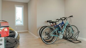 A room with a bicycle rack against the wall, a window with blinds, and a wooden floor.