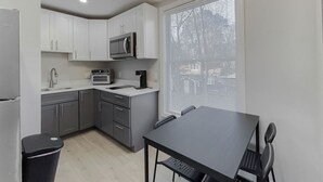 A modern kitchen with white cabinets, a microwave, and a dining table with chairs.