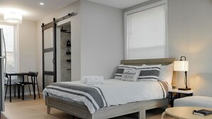 A modern bedroom with a bed, bedside table, lamp, and a sliding door closet.