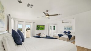 Un dormitorio con una cama grande, un ventilador de techo y vistas a un balcón.