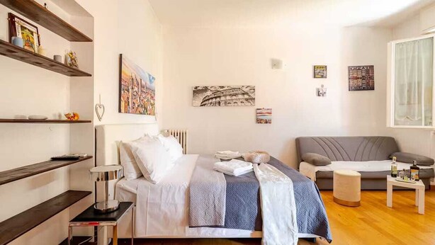 Ein modernes Schlafzimmer mit einem Bett, einem Nachttisch und einem grauen Sofa.