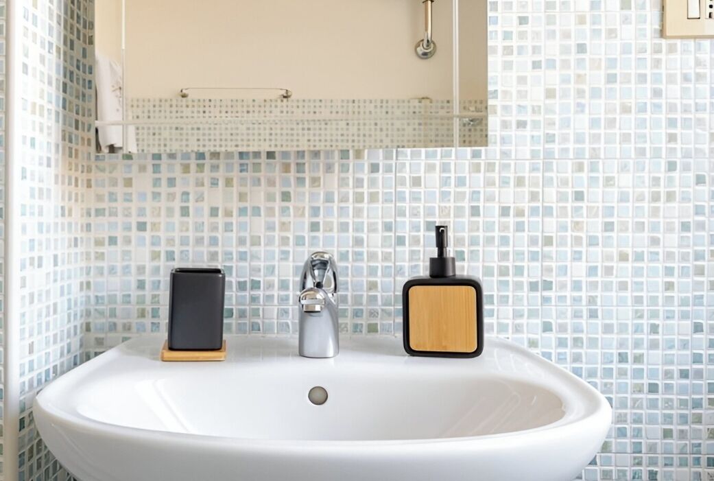 A bathroom with a white sink, a mirror above it, and a tiled backsplash.