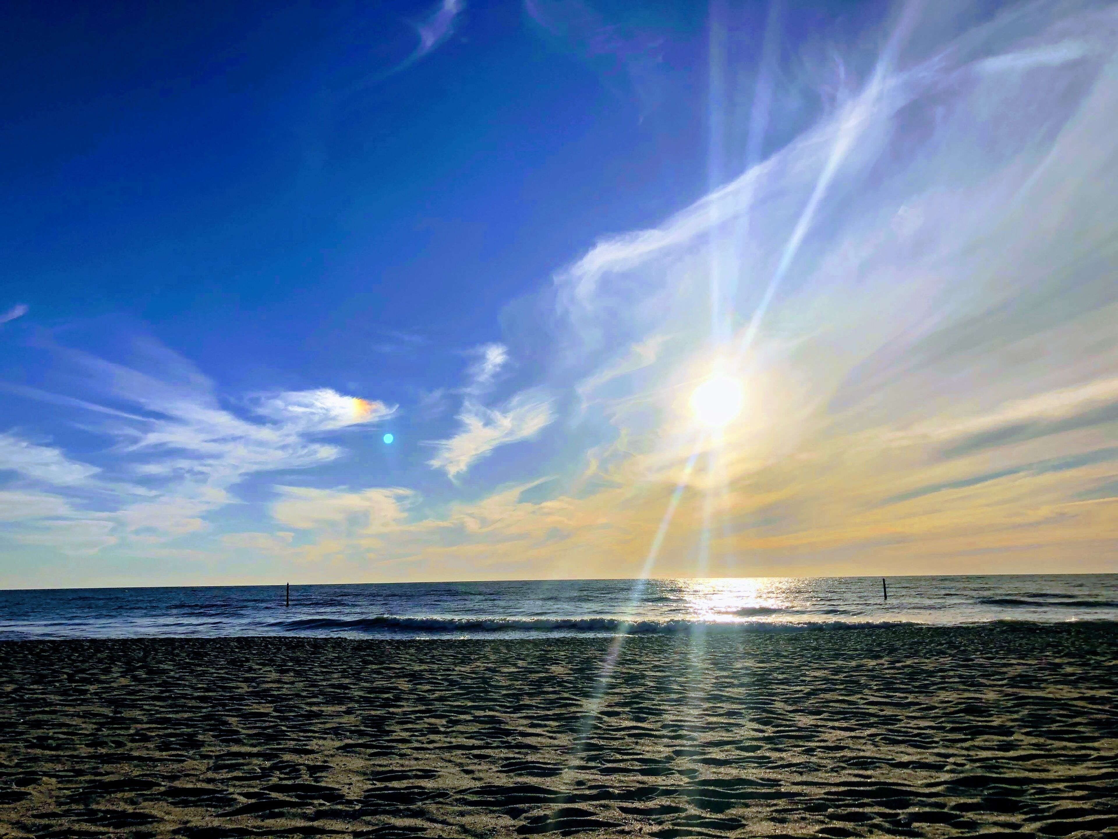 A beach with a clear sky and sunlight reflecting on the water.