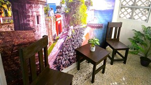 A room with a mural of a coastal scene, two wooden chairs, a small table, and a potted plant. - Lakefront with Power and Water Backup Near Airport & Beach (Carolina)