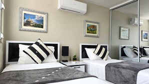 A hotel room with two beds, a bedside table with a lamp, and framed pictures on the wall. - Lakefront with Power and Water Backup Near Airport & Beach (Carolina)