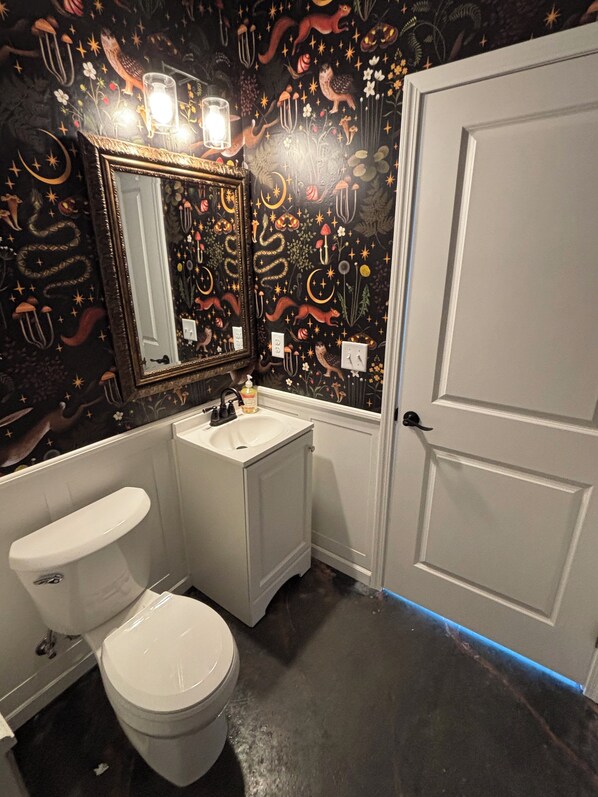 A bathroom with a white toilet, a sink, and a mirror. The walls are decorated with a black mural featuring various patterns and designs. - Parkside Nest Apartment Near Manito Park (Spokane)