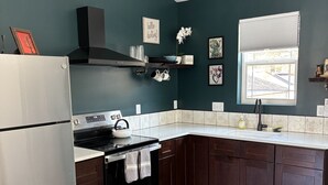 A modern kitchen with dark cabinetry, stainless steel appliances, and a window providing natural light. - Parkside Nest Apartment Near Manito Park (Spokane)