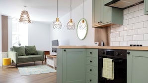 A modern kitchen with green cabinets, a black oven, and pendant lights. - Cosy-cute Miner's Cottage on the Taff Trail (Merthyr Tydfil)