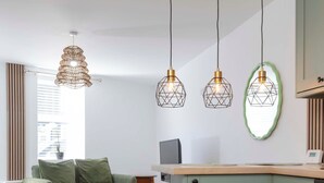 A modern kitchen with a green cabinet, a wooden countertop, and pendant lights. - Cosy-cute Miner's Cottage on the Taff Trail (Merthyr Tydfil)