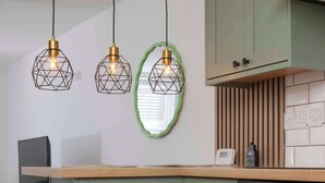 A kitchen with green cabinets, a wooden countertop, and pendant lights with geometric designs. - Cosy-cute Miner's Cottage on the Taff Trail (Merthyr Tydfil)