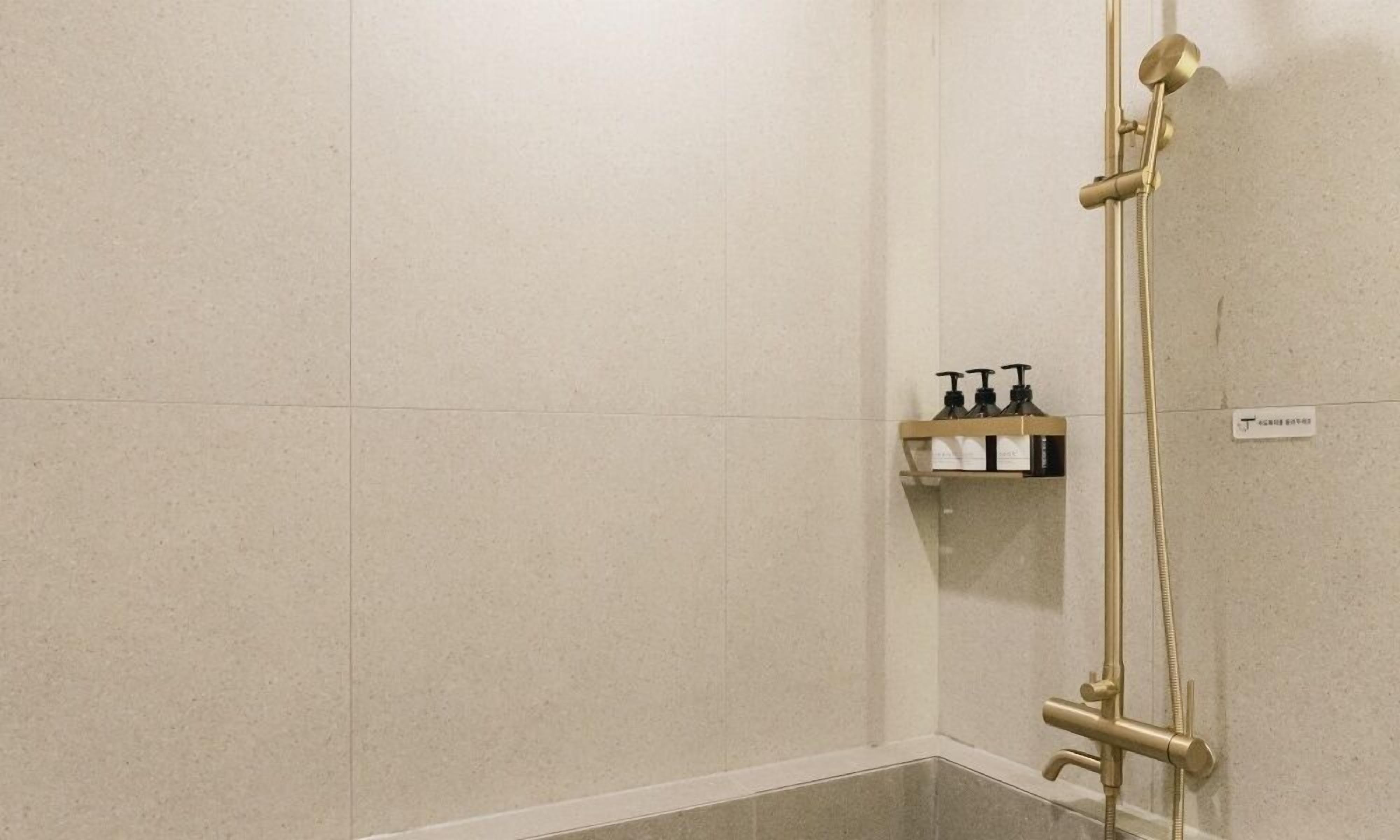 A bathroom with a shower, a towel rack, and a soap dispenser.