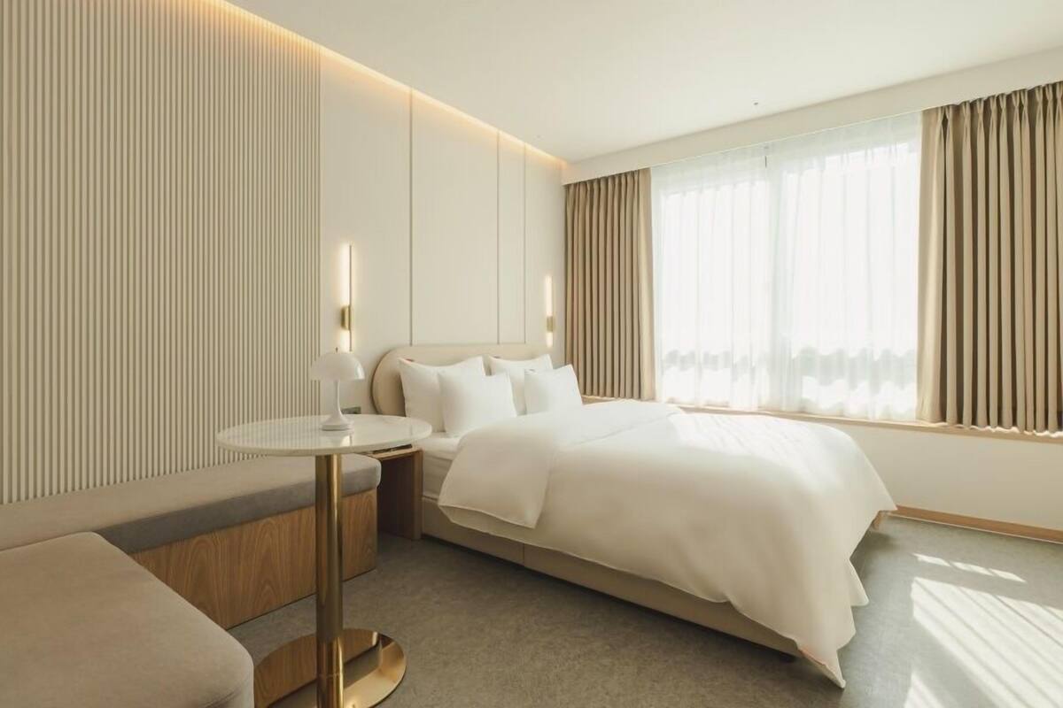 Una habitación de hotel moderna con una cama grande, una mesa redonda y una zona de estar.