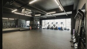 Ein Fitnessstudio mit Trainingsgeräten, Spiegeln und einem großen Fenster.