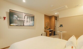 Una habitación de hotel con cama, televisión montada en la pared, una mesita redonda y un espejo.