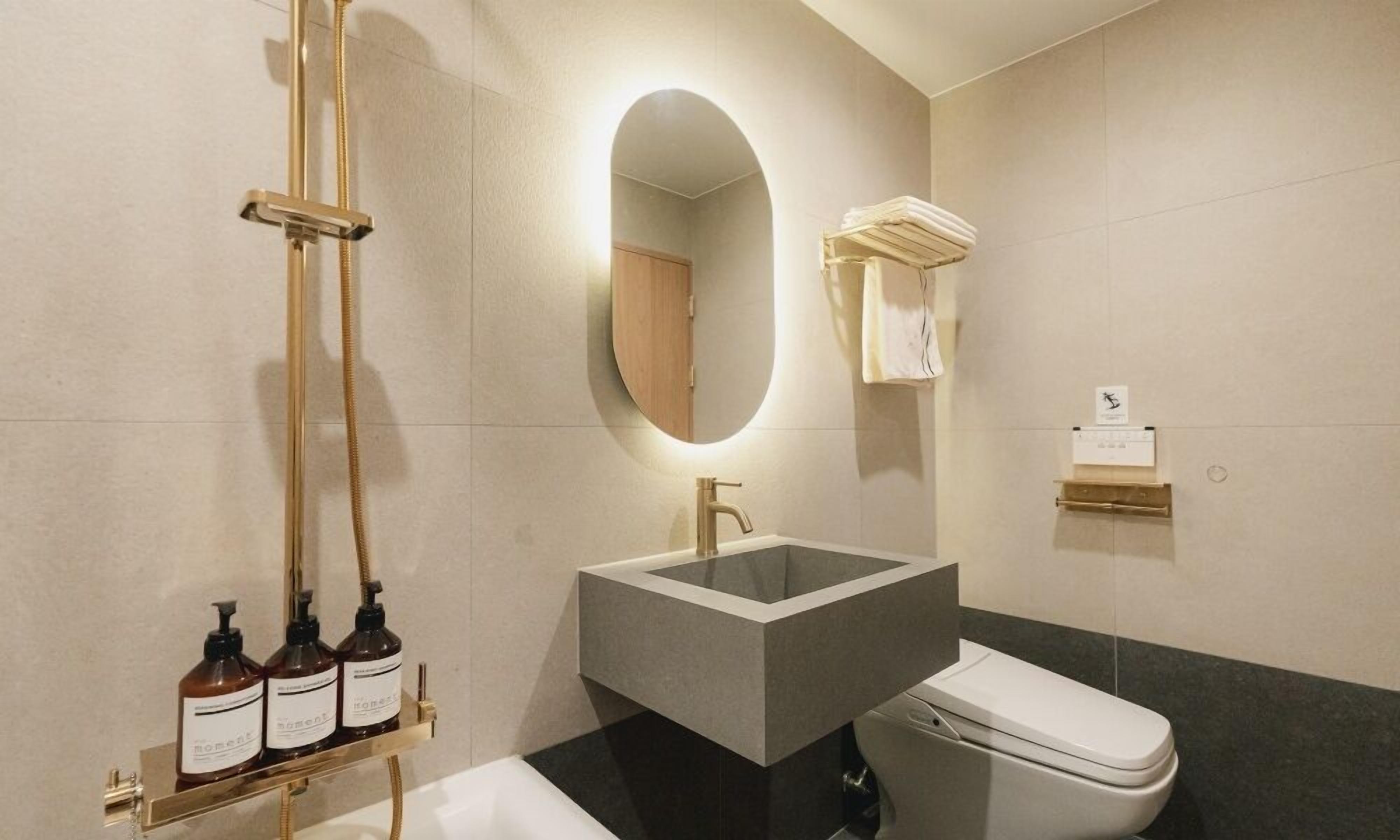 A modern bathroom with a freestanding bathtub, a vanity with a large mirror, and a toilet.