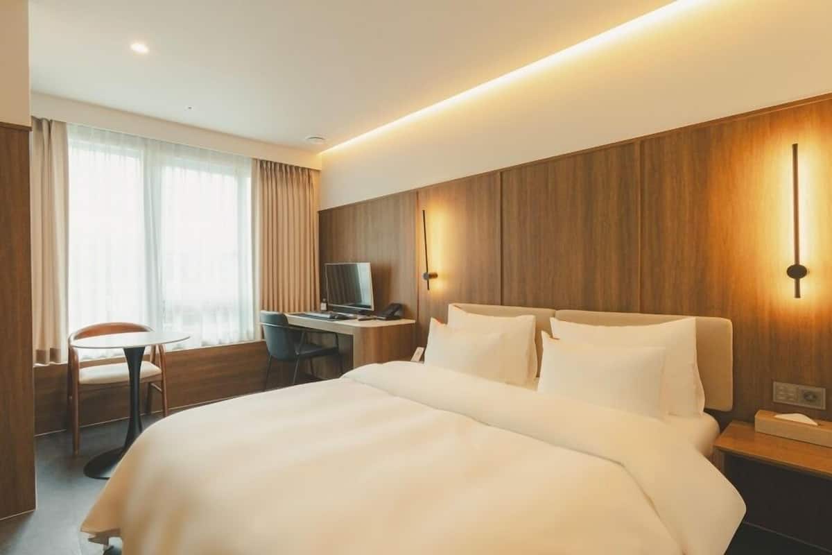 Habitación de hotel con una cama grande, un escritorio con computadora, una silla y un televisor.