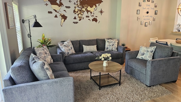 Una sala de estar con un sofá modular, dos sillones, una mesa de centro y un mapa del mundo en la pared.