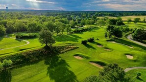 Ein Golfplatz mit gepflegten Grünflächen, Sandbunkern und einem gewundenen Weg.
