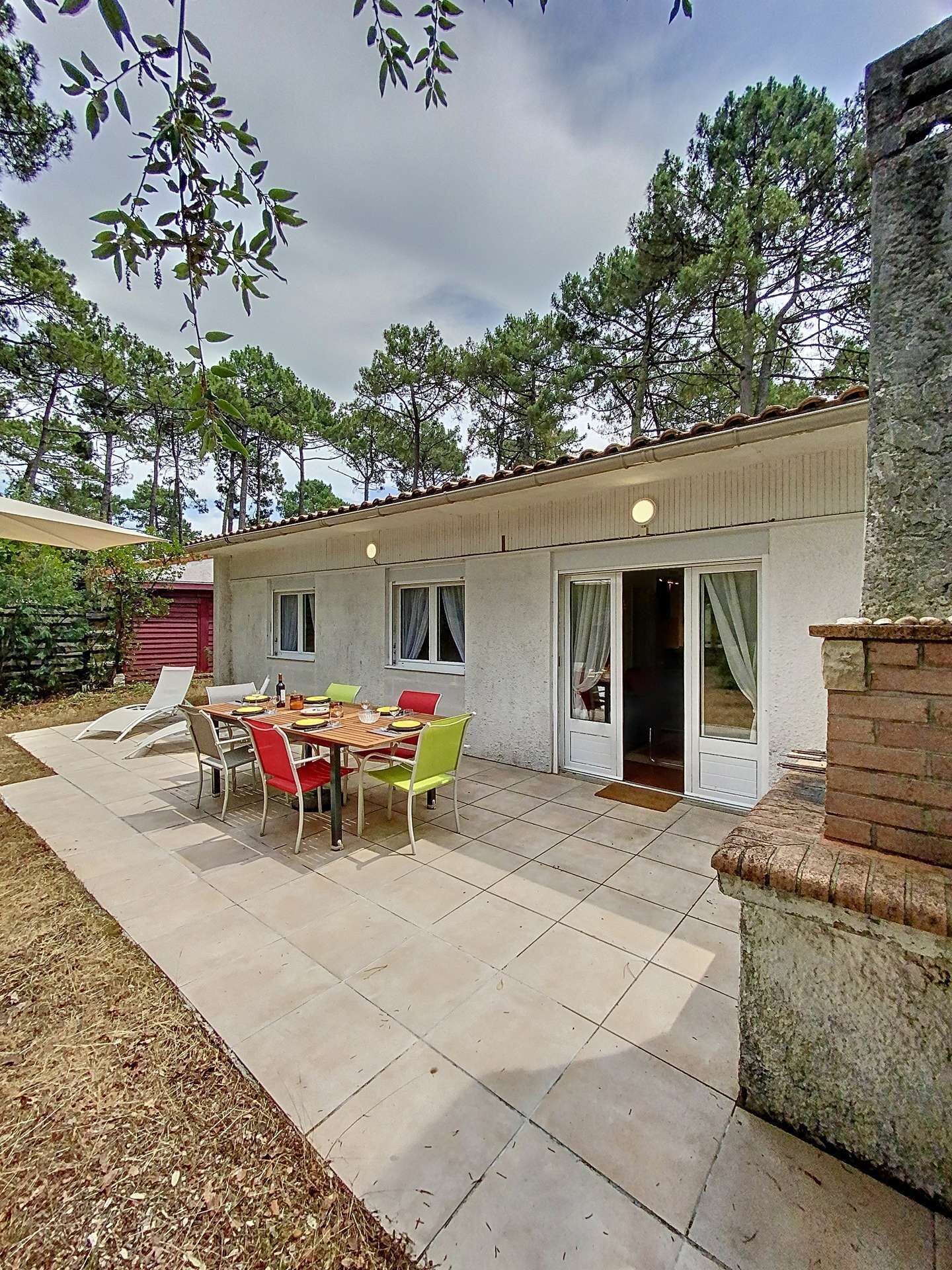 A patio with a table and chairs, a covered area, and a building with a tiled roof.