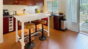 Een moderne keuken met een wit aanrecht, drie krukken en een groot raam.