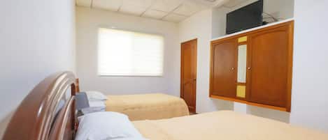 Habitación de hotel con dos camas, un armario de madera, un televisor en la pared y una ventana con persianas.