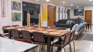 Un espace repas moderne avec une grande table, des chaises et un luminaire suspendu.