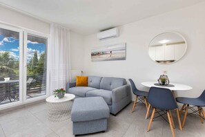 A modern living room with a grey sofa, a round table, and blue chairs.