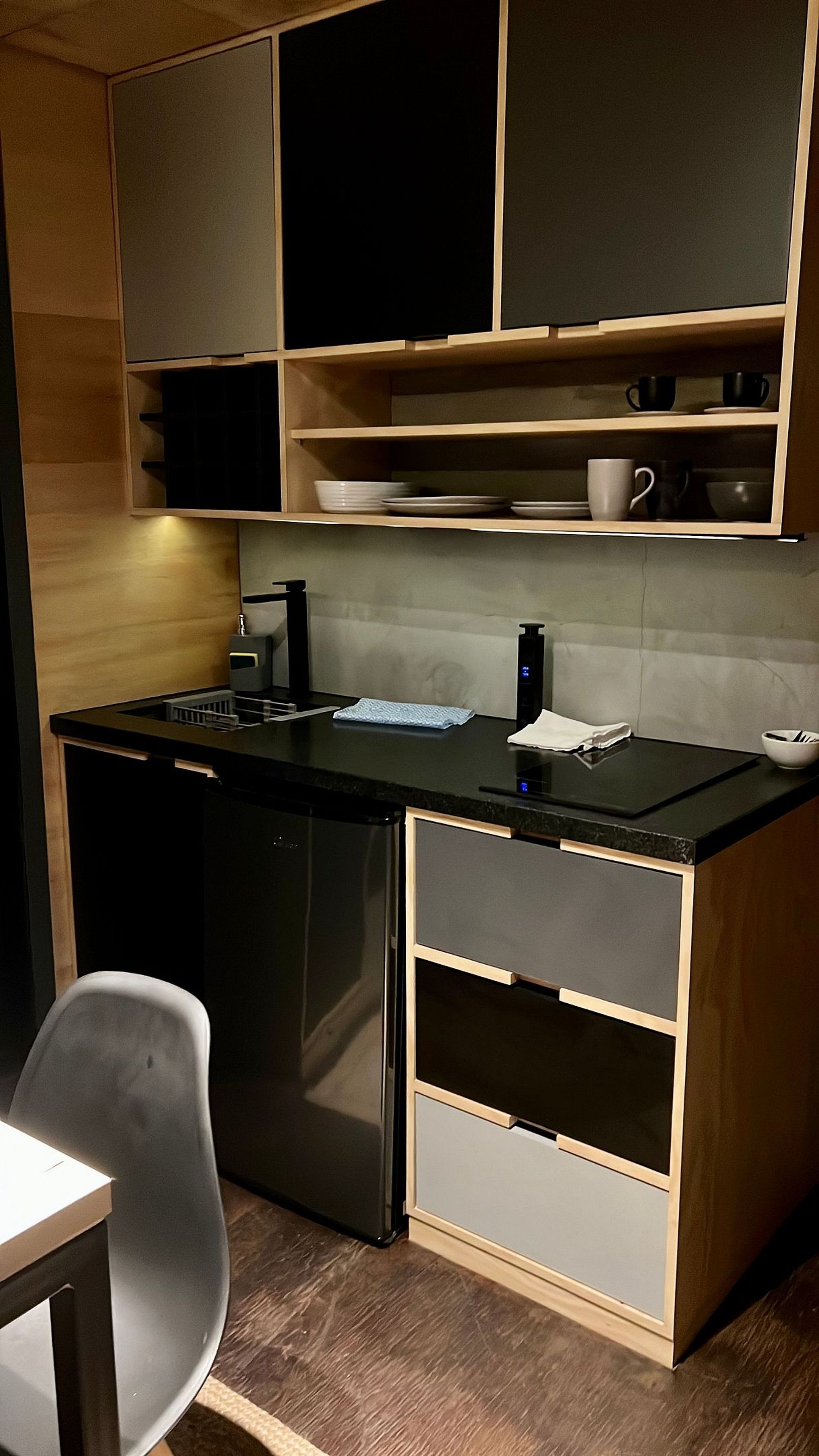 Cozinha compacta com lava-louças, pia e bancada com tábua de corte e chaleira.