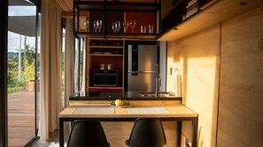 A modern kitchen with a built-in oven, a refrigerator, and a dining area with two chairs. - Moriá Village (Pirenópolis)