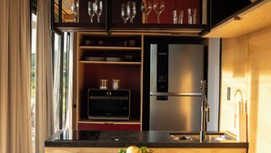 Een moderne keuken met een houten aanrecht, twee zwarte stoelen, een inbouwoven en een roestvrijstalen koelkast.