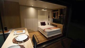 A compact bedroom with a bed, bedside table, and a television.