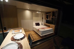 Un dormitorio pequeño con cama, mesita de noche y televisor.