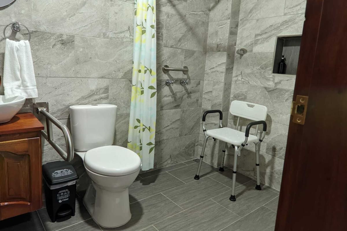 A bathroom with a toilet, bidet, and a shower chair.