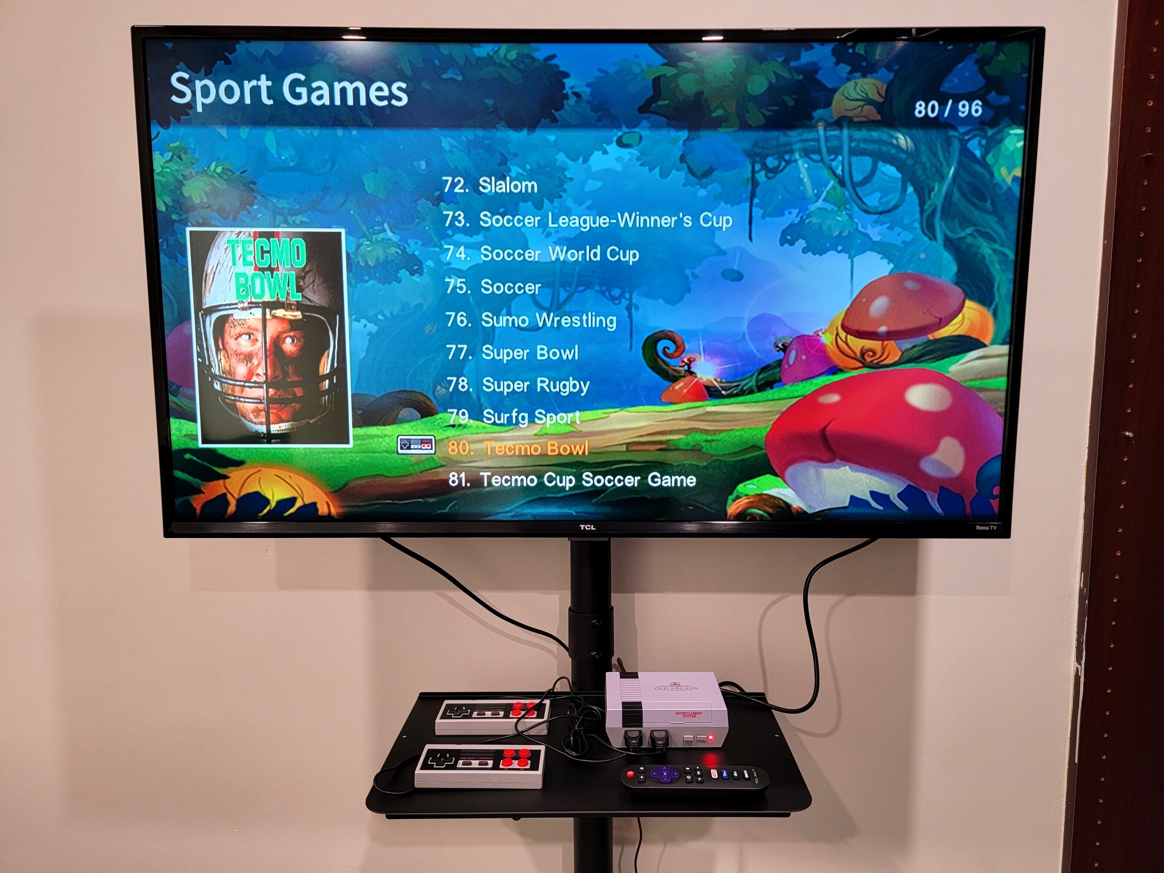 Uma televisão exibindo um menu de jogos esportivos, com opções como Slalom, Liga de Futebol – Copa do Vencedor e Tecmo Bowl.