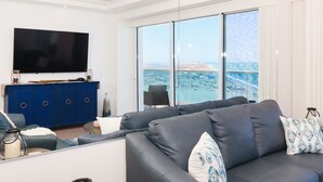 A modern living room with a large flat-screen TV, a blue cabinet, and a sofa with patterned cushions.
