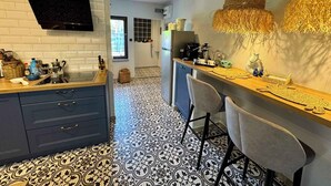A modern kitchen with a black and white patterned floor, a built-in oven, and a TV mounted on the wall.