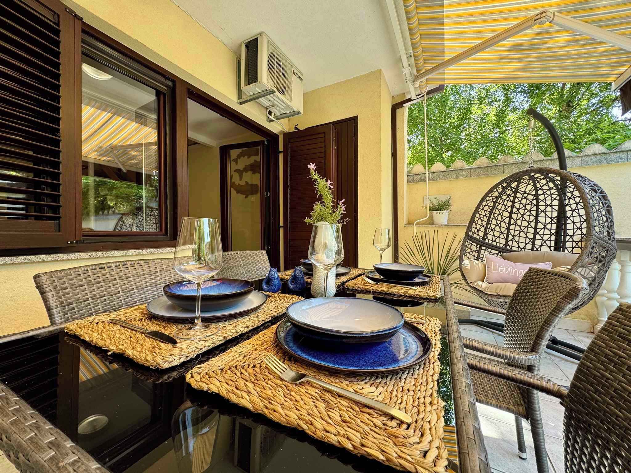 An outdoor dining area with wicker furniture, a hanging chair, and a table set with plates and glasses.