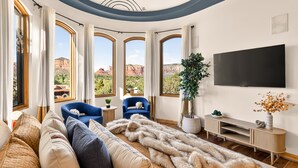 Ein modernes Wohnzimmer mit großem Fenster, Flachbildfernseher und gemütlicher Sitzecke.
