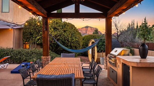 Eine Terrasse im Freien mit Holztisch und -stühlen, einer Hängematte und einem Grillbereich.