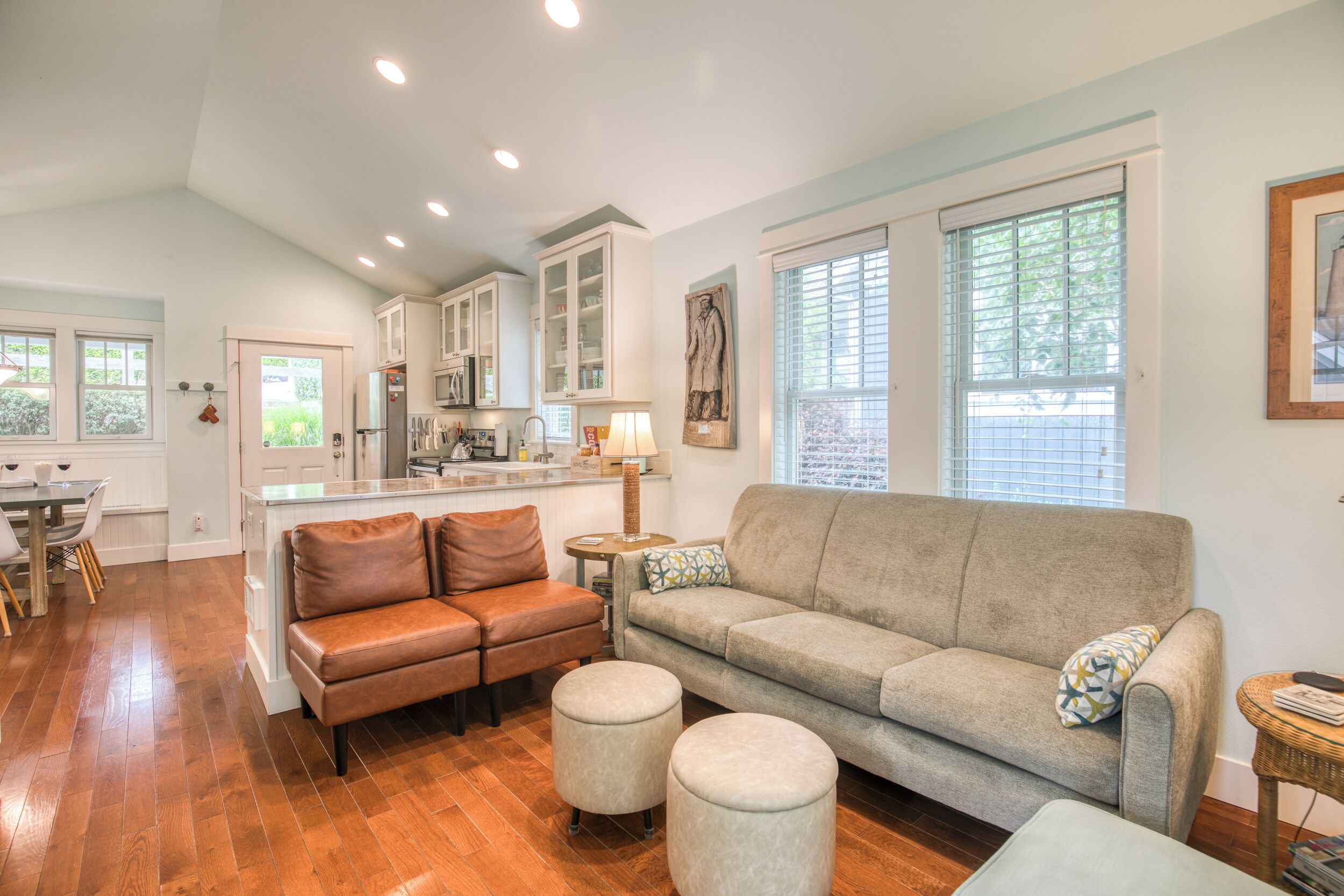 A spacious living area with a sofa, ottomans, and a dining table.