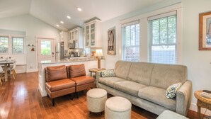A spacious living area with a sofa, ottomans, and a dining table. - 5 min. Walk to Town & Beach, Greenbelt Views + Private Backyard (Pacific Beach)