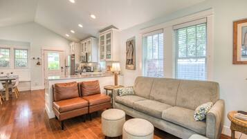 A spacious living area with a sofa, ottomans, and a dining table.