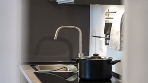 Een moderne keuken met een roestvrijstalen spoelbak, een zwarte pan op het fornuis en een strakke kraan.