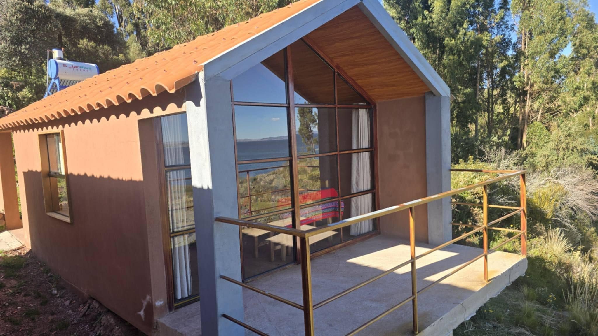 Une petite cabane avec un toit en pente, de grandes fenêtres et un balcon.